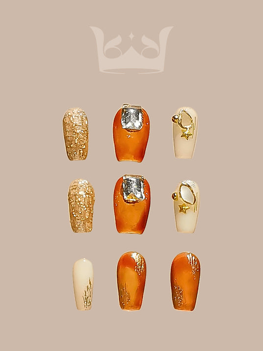 These warm-colored nails with glitter, metallic accents, 3D embellishments, gradient effect, and glossy finish are perfect for a bold statement or special occasion.