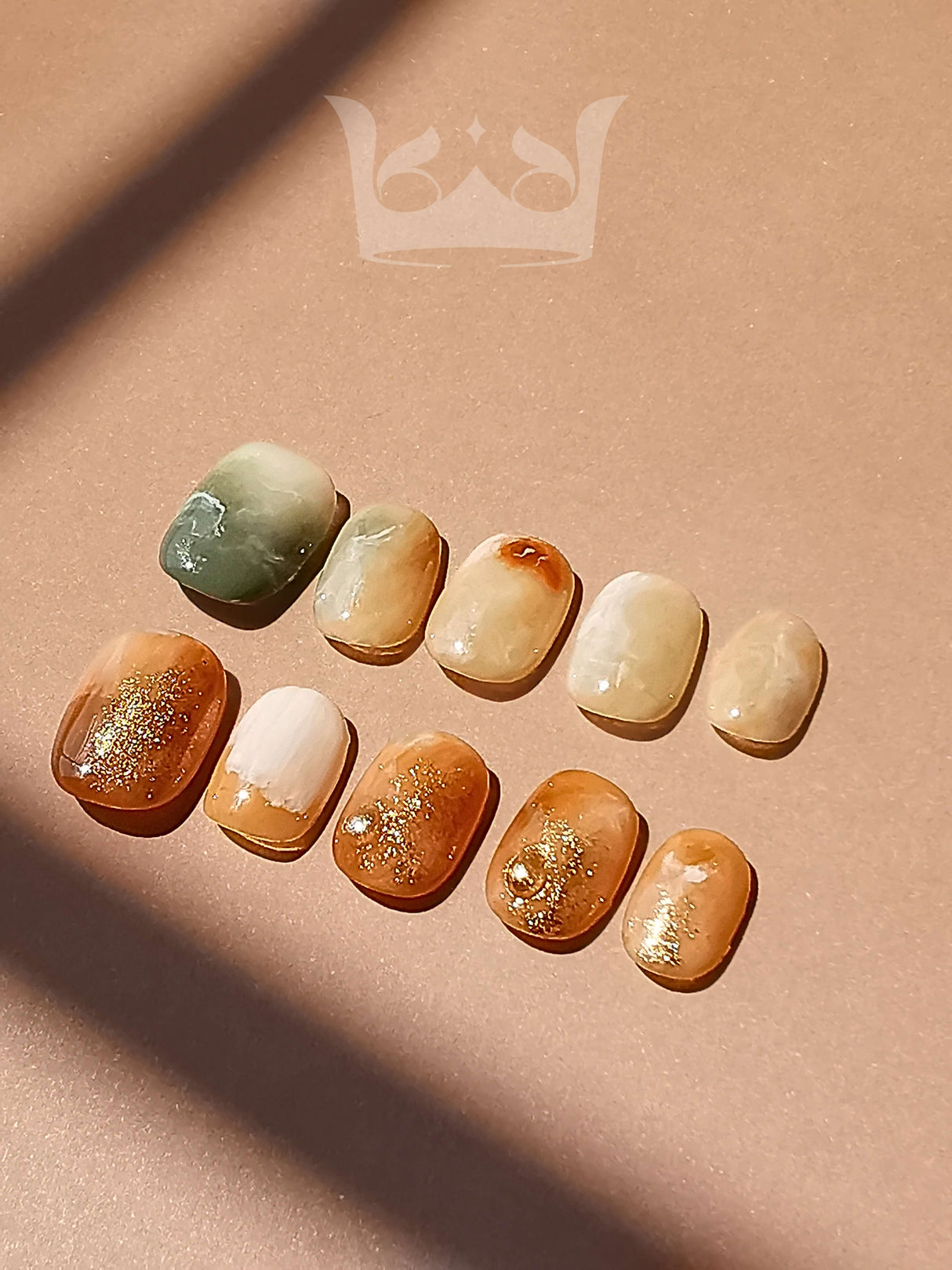 These press-on nails complementing a bohemian or nature-inspired fashion style. They feature a marbling effect, gold flakes, and a combination of glossy and matte finishes