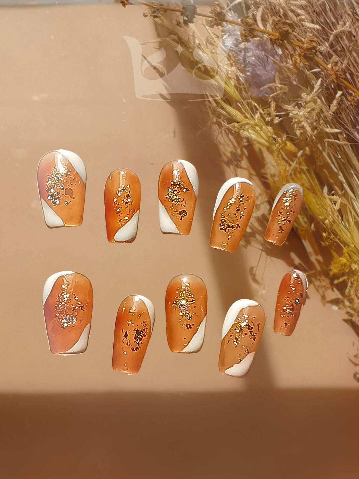 These acrylic nails are for cute purposes. The design includes gold glitter and white swirls, marketed towards fashion-conscious individuals. The neutral background highlights the design.