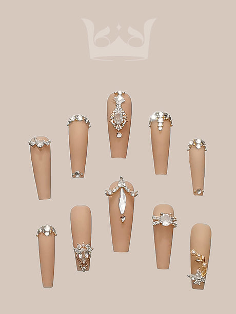 Opulent and glamorous nails with rhinestones, metallic accents, and pearls for special occasions. Neutral polish provides a subtle backdrop for the ornate decorations.