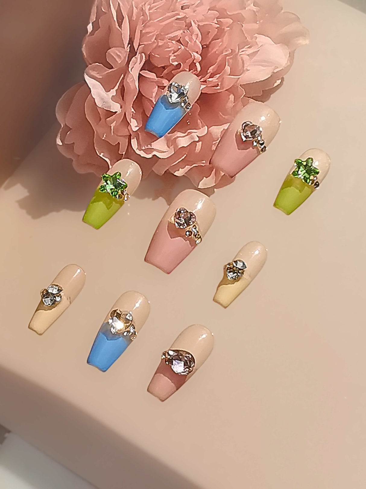 Fashionable acrylic nails with varying designs and colors, adorned with rhinestones and crystals, suitable for special occasions and showcasing latest trends.