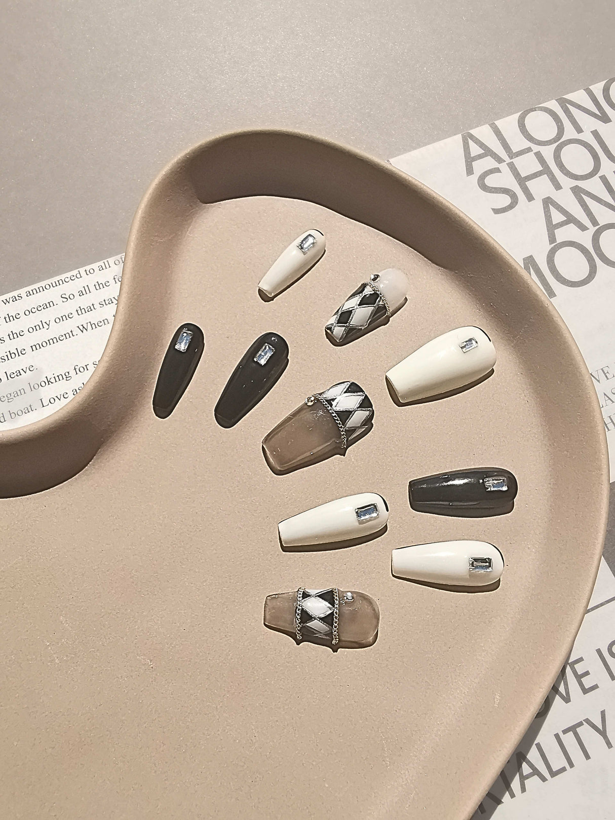 Luxurious nails with a monochromatic color scheme, featuring pearls, rhinestones, geometric patterns, 3D elements, and mixed textures for a high fashion statement.