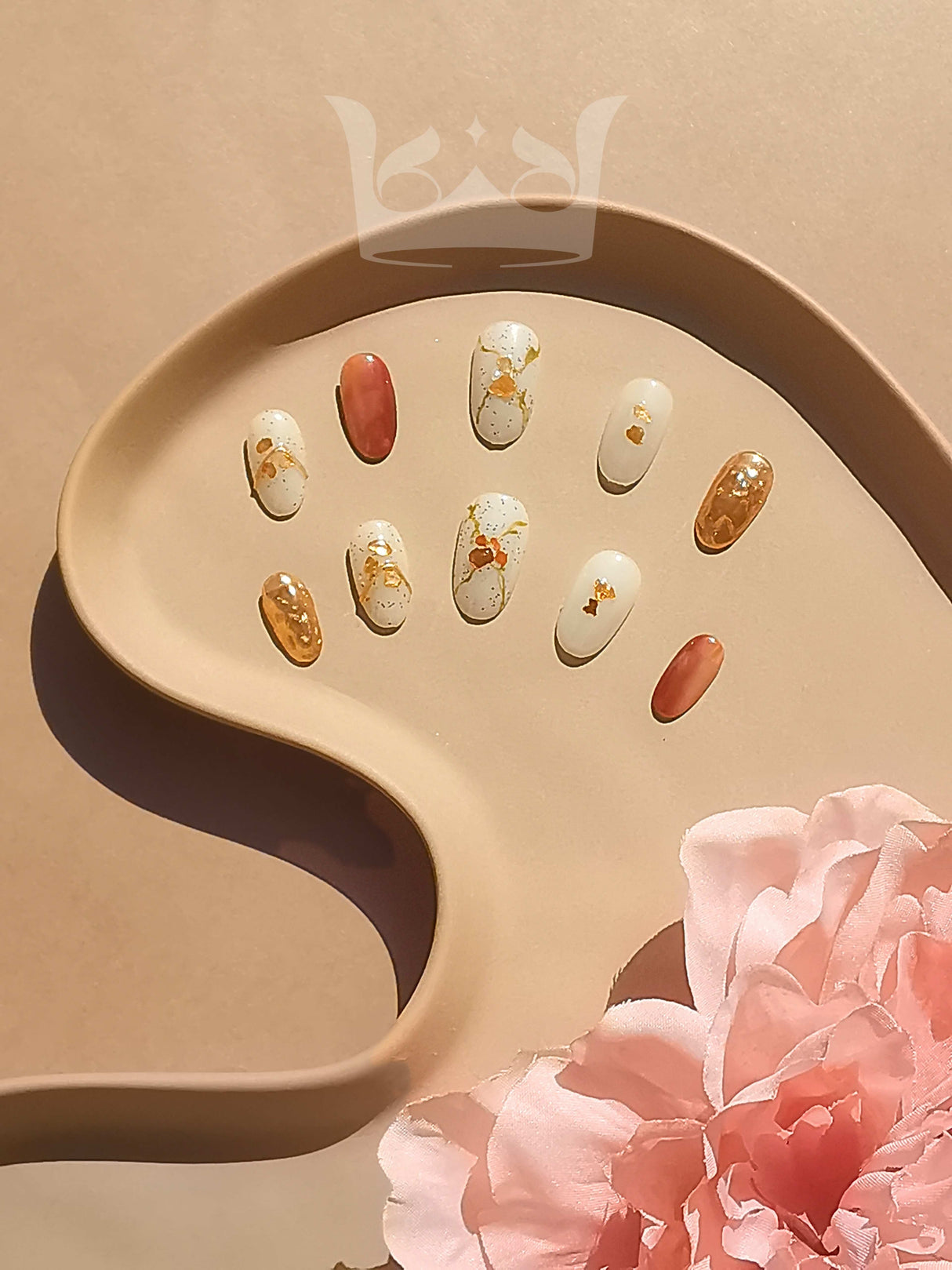 These press-on nails feature abstract patterns, gold flakes, and shades of white, gold, and brown. The overall aesthetic is elegant and suitable for special occasions.