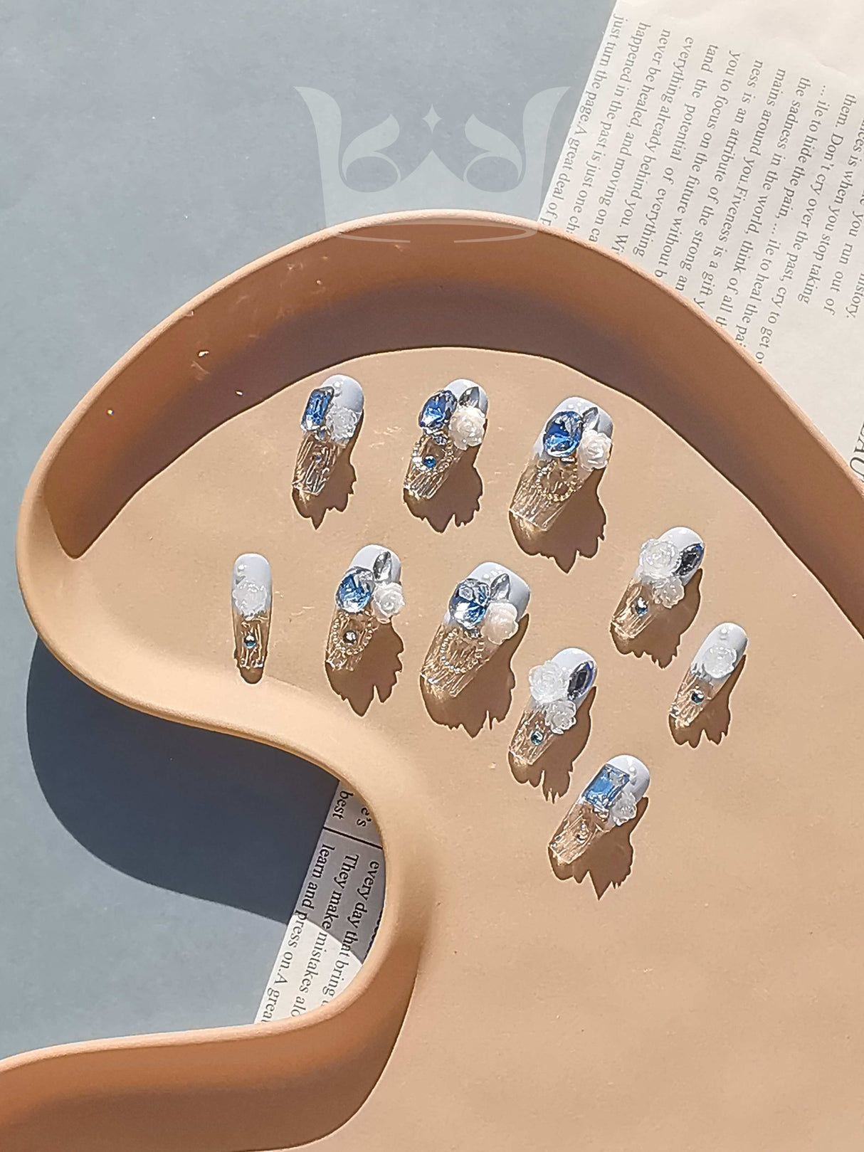 Intricate and elegant nails with blue diamonds, 3D flowers, and metallic accents are  for a special occasion. Inspired by floral and vintage jewelry themes.