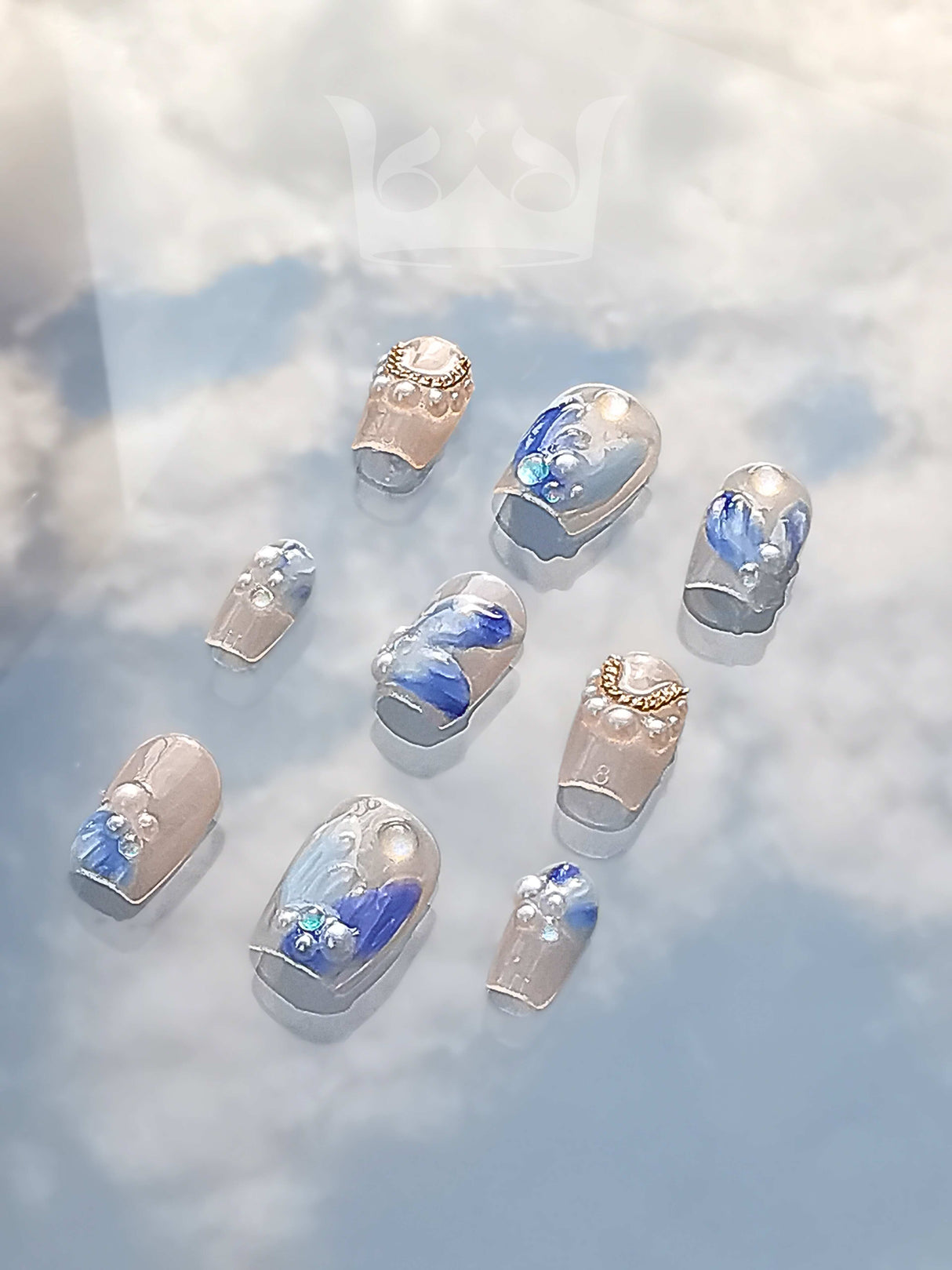 These press-on nails are feature gold embellishments, blue floral patterns, and gem-like stones for an elegant and fancy aesthetic.