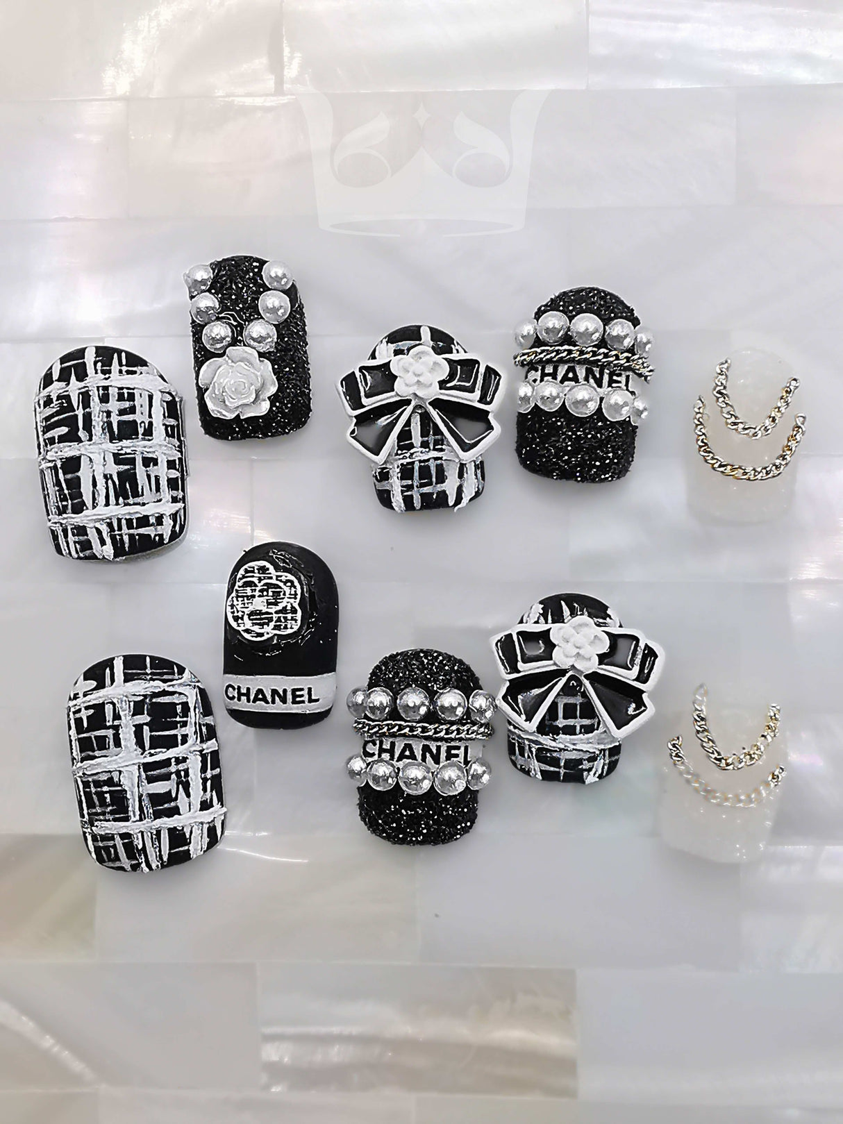Luxurious nails with a monochromatic color scheme, featuring pearls, rhinestones, geometric patterns, 3D elements, and mixed textures for a high fashion statement.