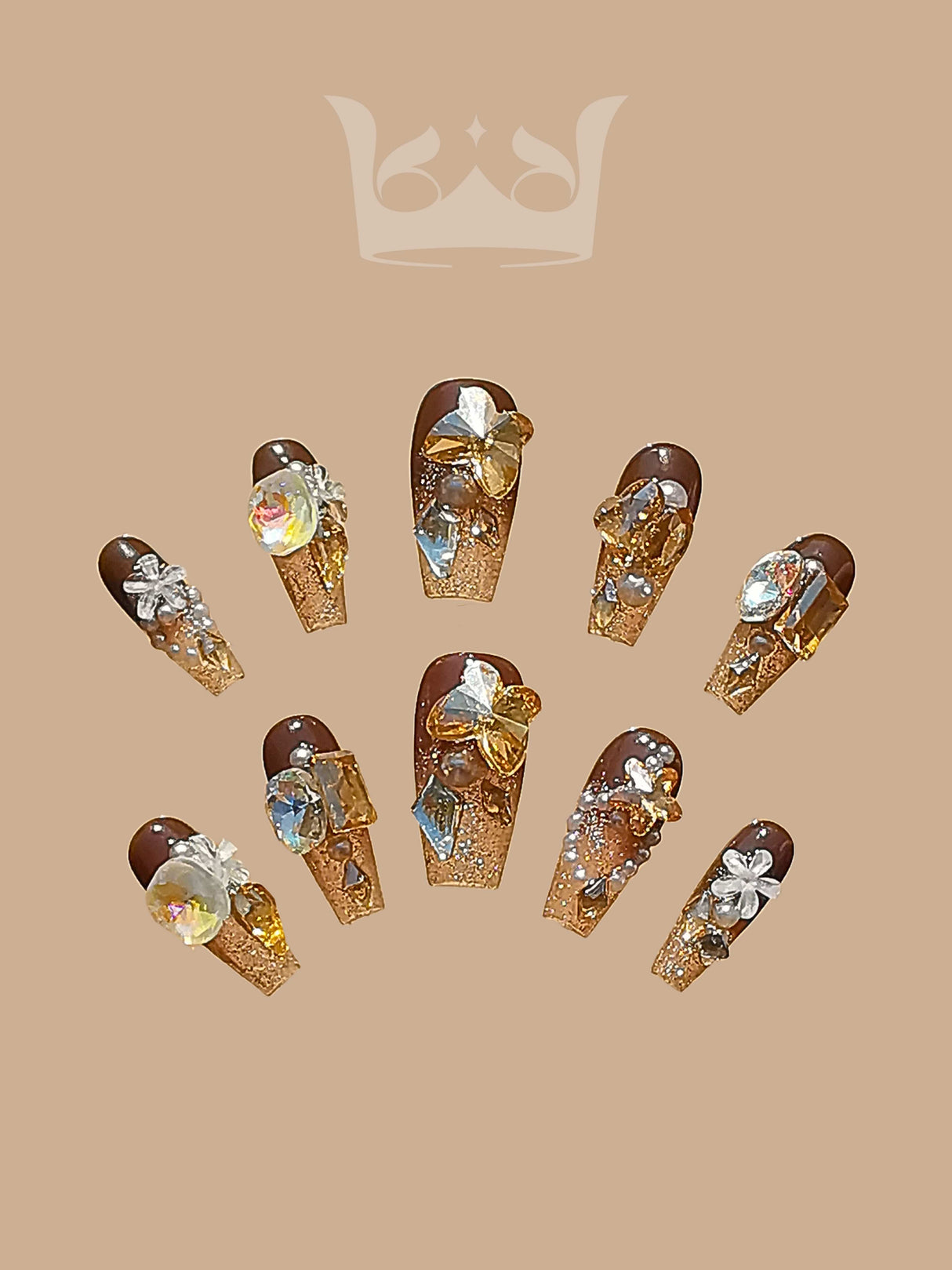 Opulent nails with warm, golden-brown base color, glitter, rhinestones, gems, and 3D embellishments. Coffin shape and length add to luxurious feel. Ideal for special occasions.