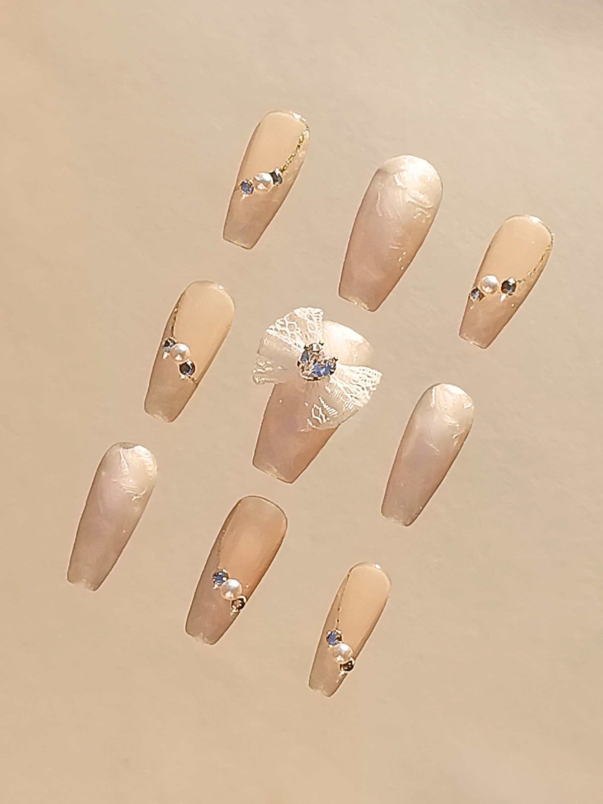 Luxurious nails with a monochromatic color scheme, featuring pearls, rhinestones, geometric patterns, 3D elements, and mixed textures for a high fashion statement.