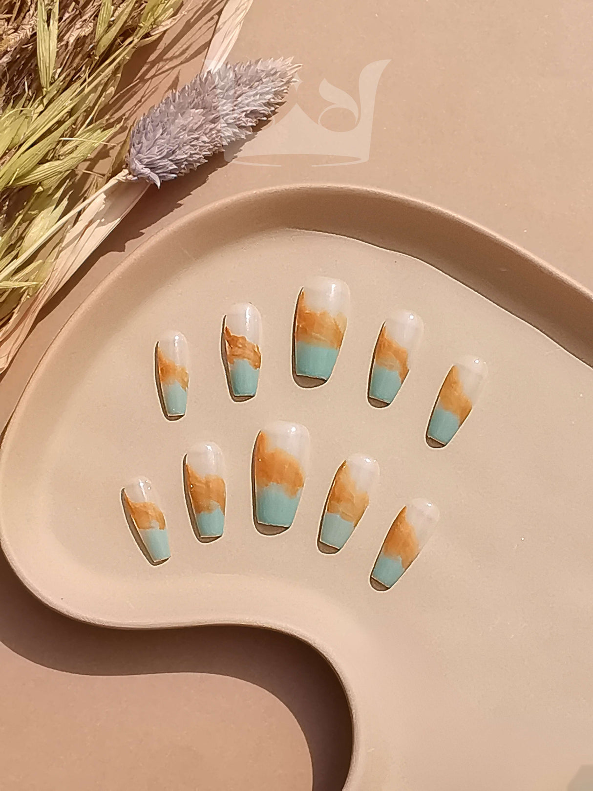 These press-on nails are a fashion accessory featuring a marbled effect in shades of turquoise, brown, and white. They have a square shape and a neutral-toned surface.
