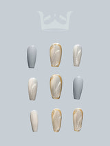 These acrylic nails come in varying lengths and shapes with a cool-toned gray and creamy color scheme, gold foil accents.