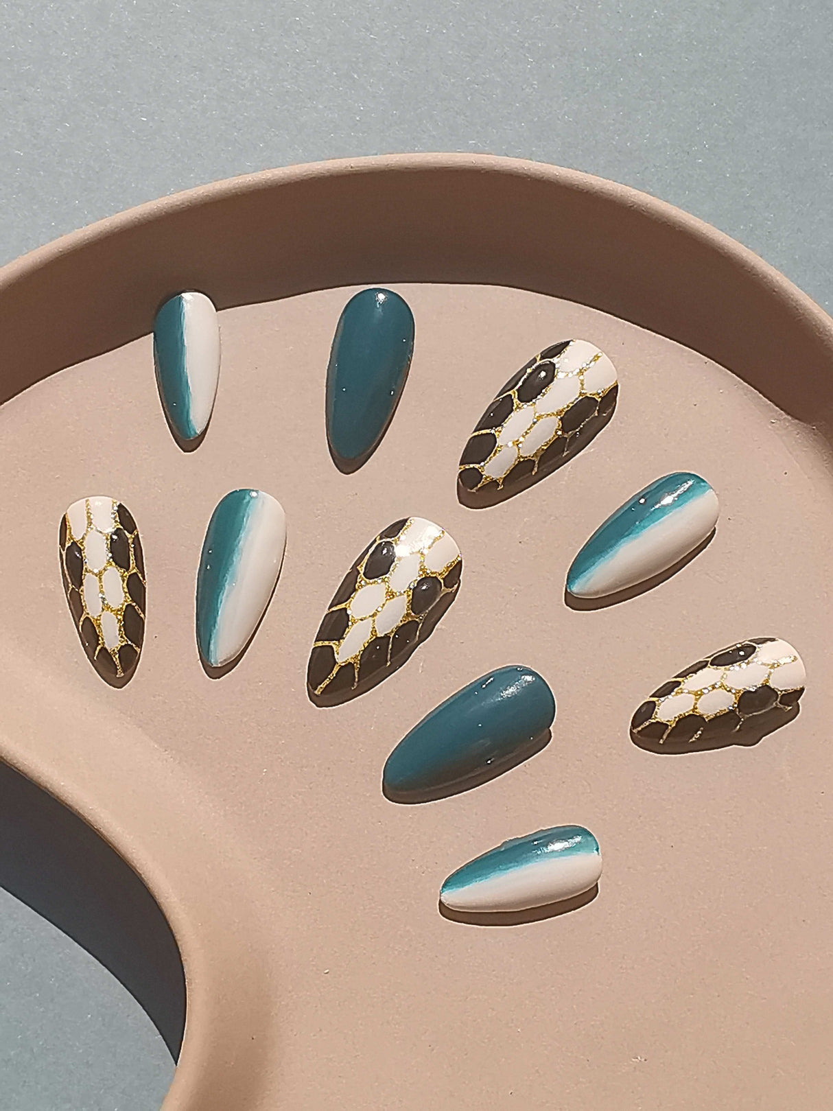 These press-on nails feature solid colors, a glossy finish, an almond shape, and a tortoiseshell pattern.