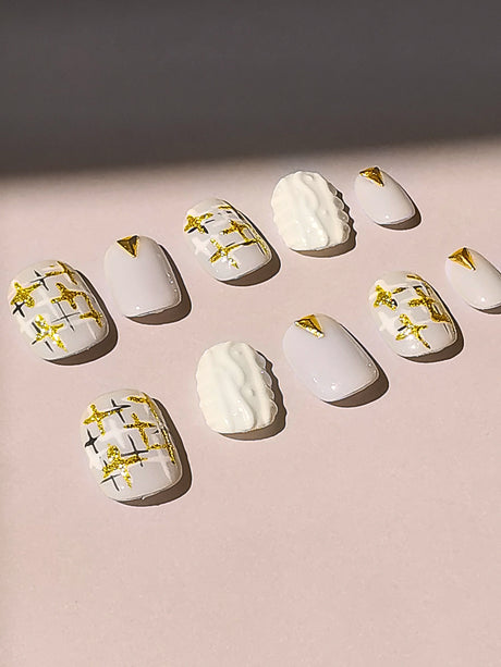 These press-on nails have a white base with gold embellishments and a textured design, and are intended for fashion-forward individuals who enjoy experimenting with different styles and trends.