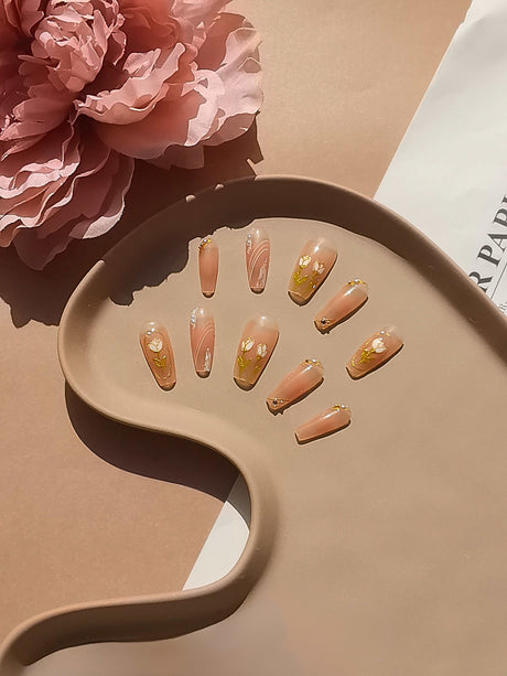 These press-on nails are perfect for special occasions like weddings or formal events. They have a neutral base color with gold accents and a medium length with a rounded tip 
