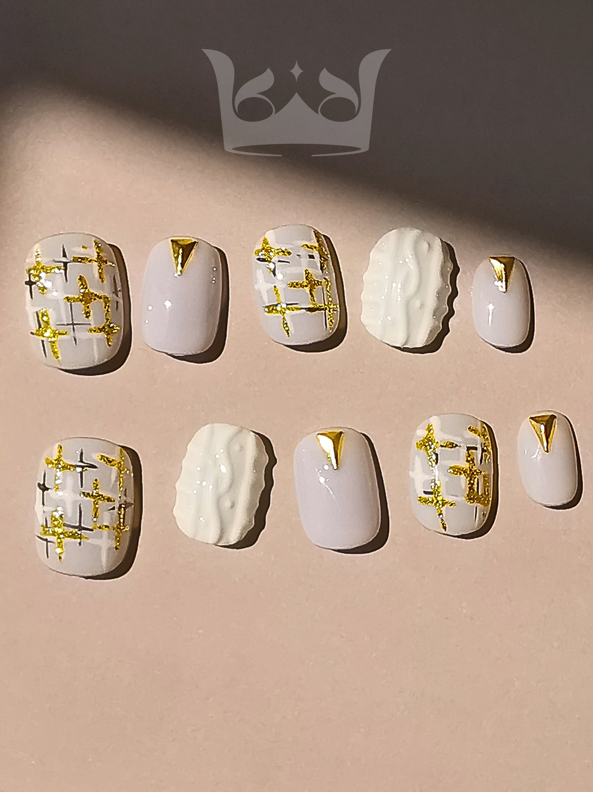 These press-on nails are perfect for a special occasion, featuring a pastel purple base with gold geometric patterns and a textured accent nail for a chic and fancy look.