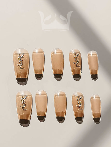 These press-on nails are perfect for special occasions like weddings or photoshoots. They have a French manicure style with a nude base color, black tips, and gold embellishments.