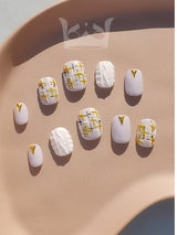These pre-designed nails offer a white and gold color scheme, textured patterns, metallic detailing, and geometric embellishments for a chic and stylish look.