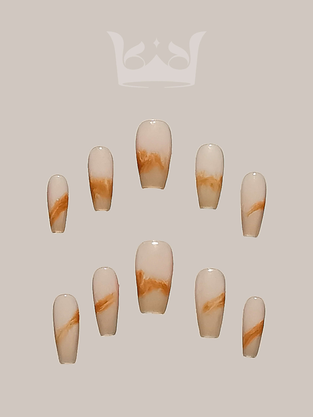 These press-on nails includes a marbled effect with swirls of white and shades of brown or tan, a symmetrical pattern. They are styled in a coffin or ballerina nail shape.