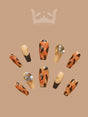 These fall-themed nails have a warm color palette, gold leaf accents, varying sizes, and a versatile design suitable for casual or formal occasions.