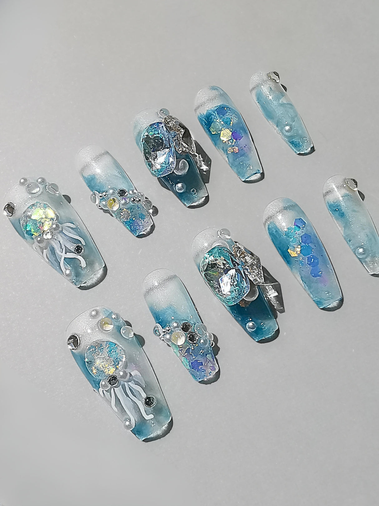 Add a winter wonderland touch to your manicure with these acrylic nail tips decorated with glitter, sequins, and diamonds resembling icy formations or snowflakes. 