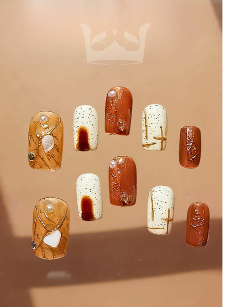 Fashionable and unique manicure with glossy finish, speckles, streaks, gem-like embellishments, and earthy color palette for an elegant and creative aesthetic.