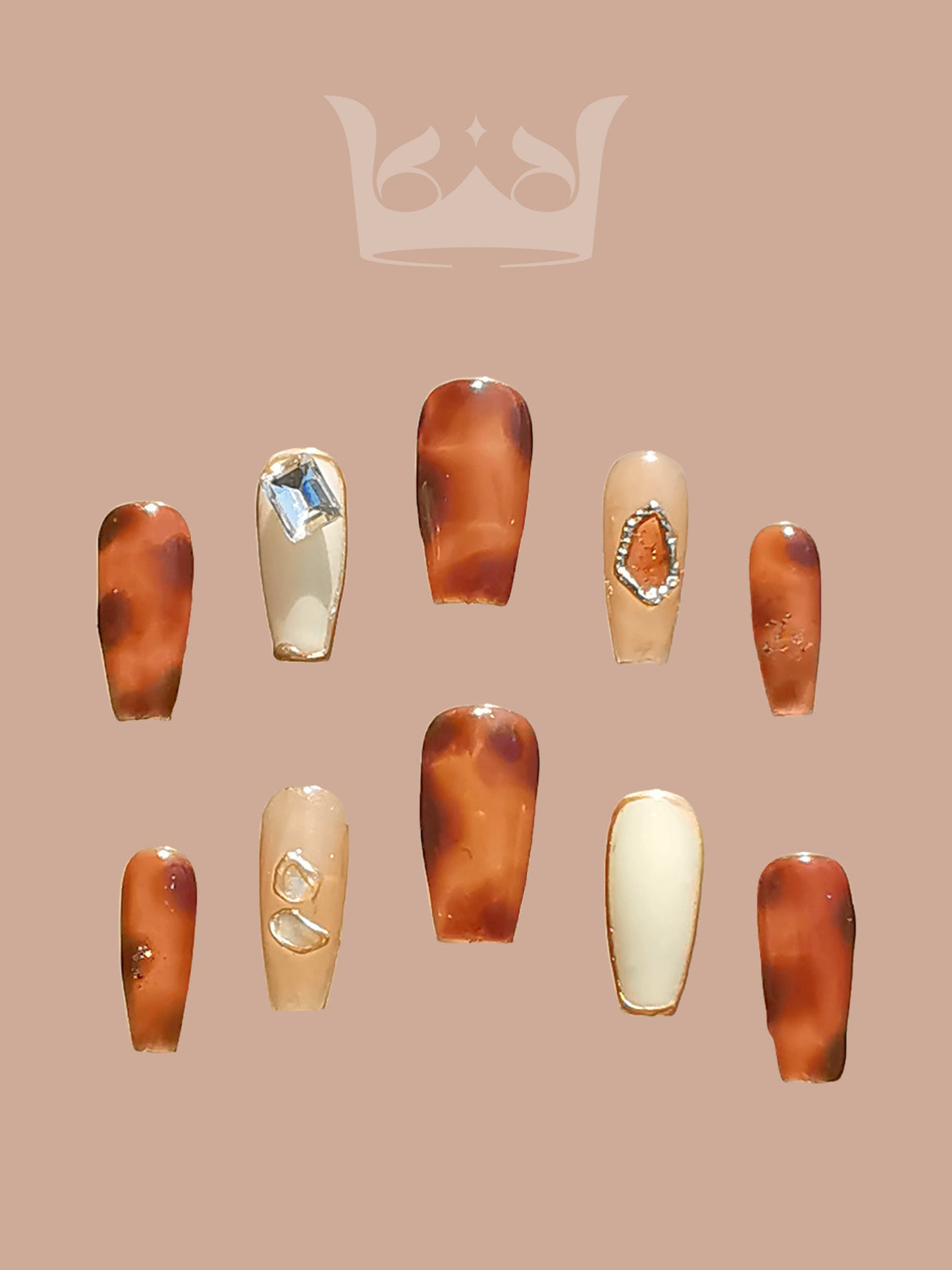Fashionable and bold manicure statement with warm brown, amber, and translucent tones, gem-like adornments, gold frames, and embedded rings/hoops.