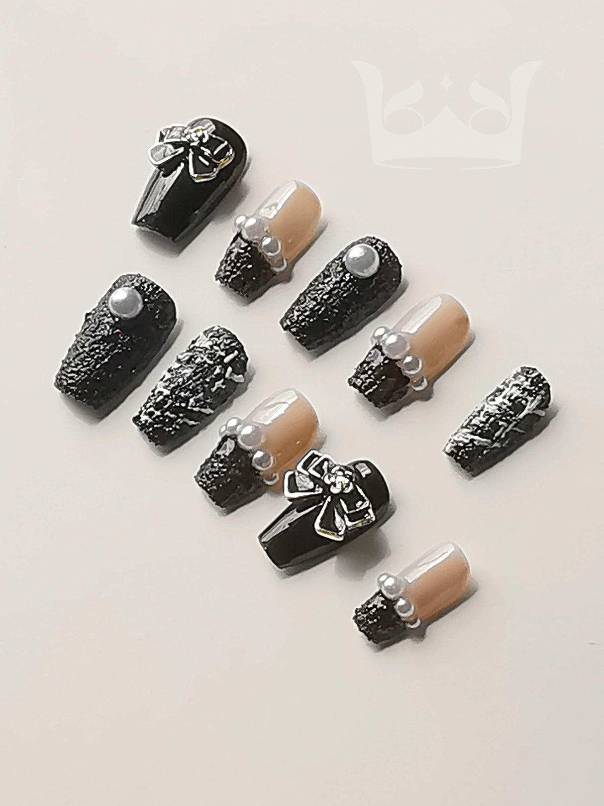 Sophisticated nails with black and nude colors, pearls, metallic details, bow accents, and mixed finishes are perfect for special occasions or a night out.