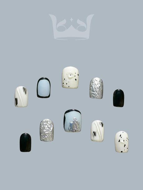 Fashionable nails with solid colors, metallic textures, and abstract designs in black, white, and silver tones for a modern and fancy style.
