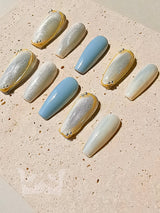 These press-on nails have a muted color palette, metallic accents, embellishments, glossy finish, and long, oval or almond shape for a luxurious and ornate appearance.