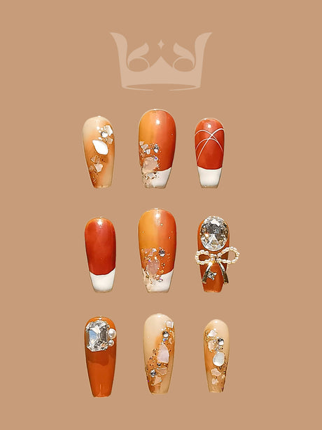These autumnal nails feature warm colors, gold flakes, diamonds, and a large crystal embellishment for an elegant touch. Perfect for special occasions or seasonal flair.