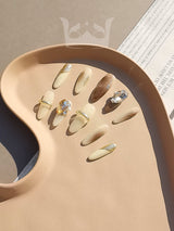 Luxurious gold foil accents and large rhinestones make these long, possibly almond or stiletto shaped nails perfect for a fancy occasion and fashion statement.