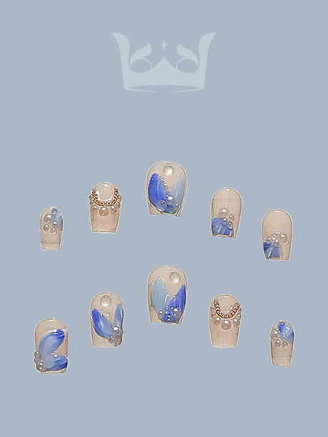 These nails featuring blue and silver colors, rhinestones, metallic accents, marble effect, abstract art, and a glossy finish. For those with a desire for bling, shine, and unique designs.