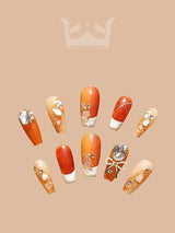 Intricately designed nails with warm, peachy, and orange tones, embellished with rhinestones, glittery stones, and floral patterns, suitable for special occasions or fashion statements.