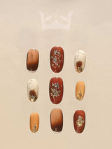 These press-on nails are for special occasions, feature deep brown and creamy off-white colors with golden glitter and floral patterns, and a rounded tip for comfort.