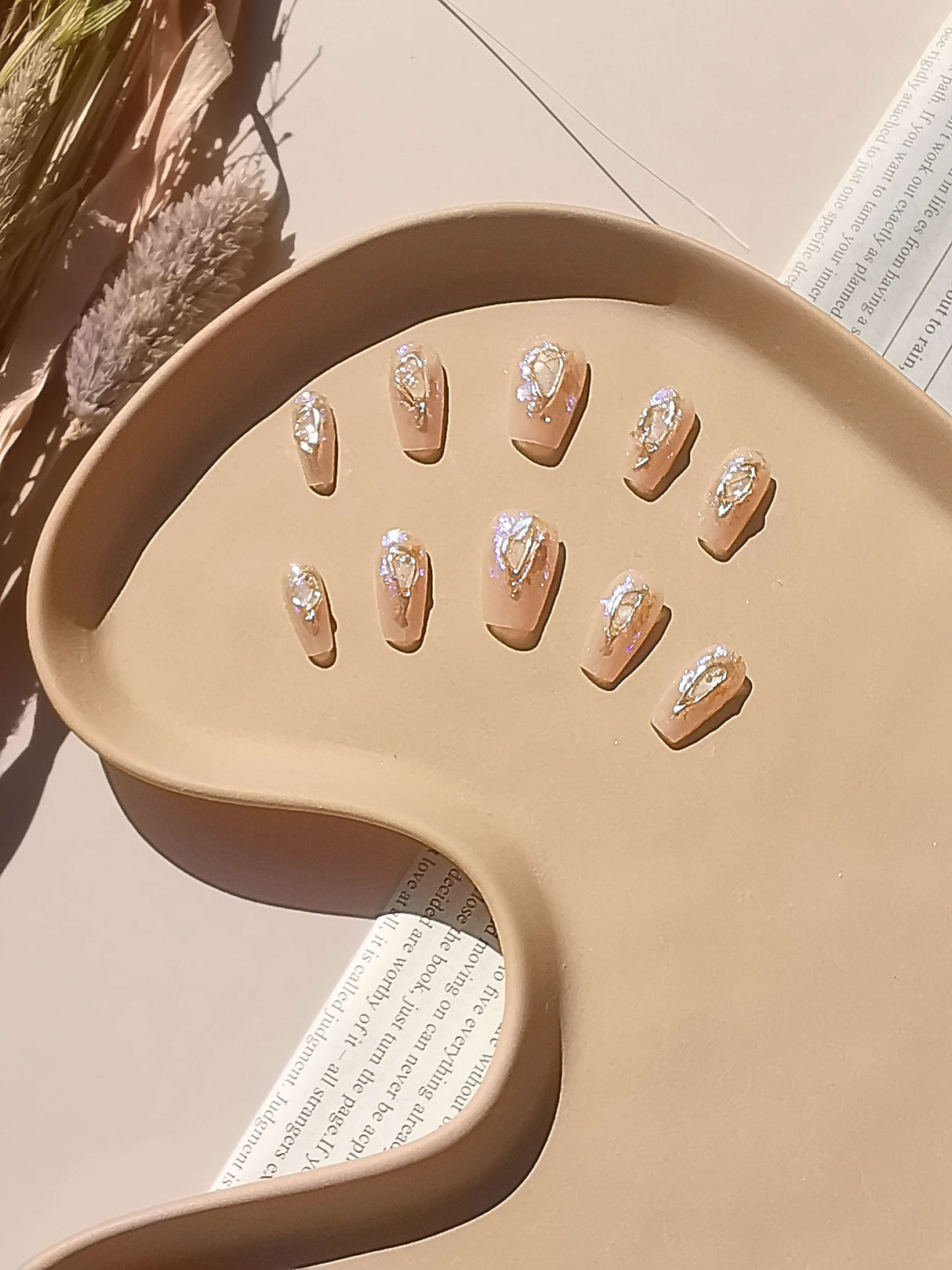 These press-on nails are for cute purposes, with a glamorous and fancy design. They feature a metallic gold base and a white pattern, displayed with a natural light shadow. 
