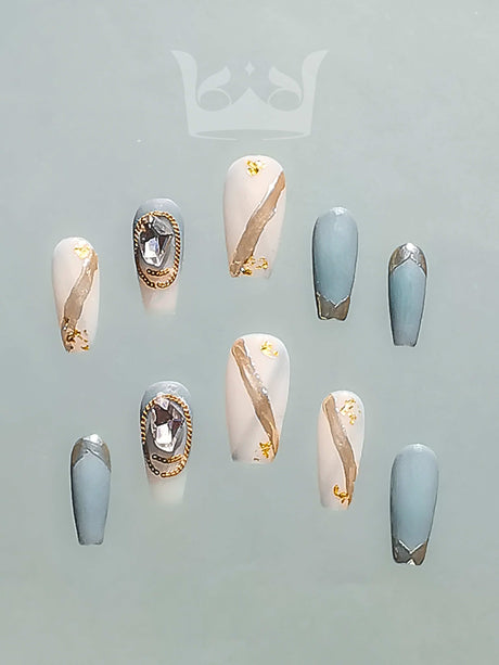 These stiletto-shaped nails with gold foil accents and large rhinestones are a stylish fashion accessory for special occasions or as a statement piece.