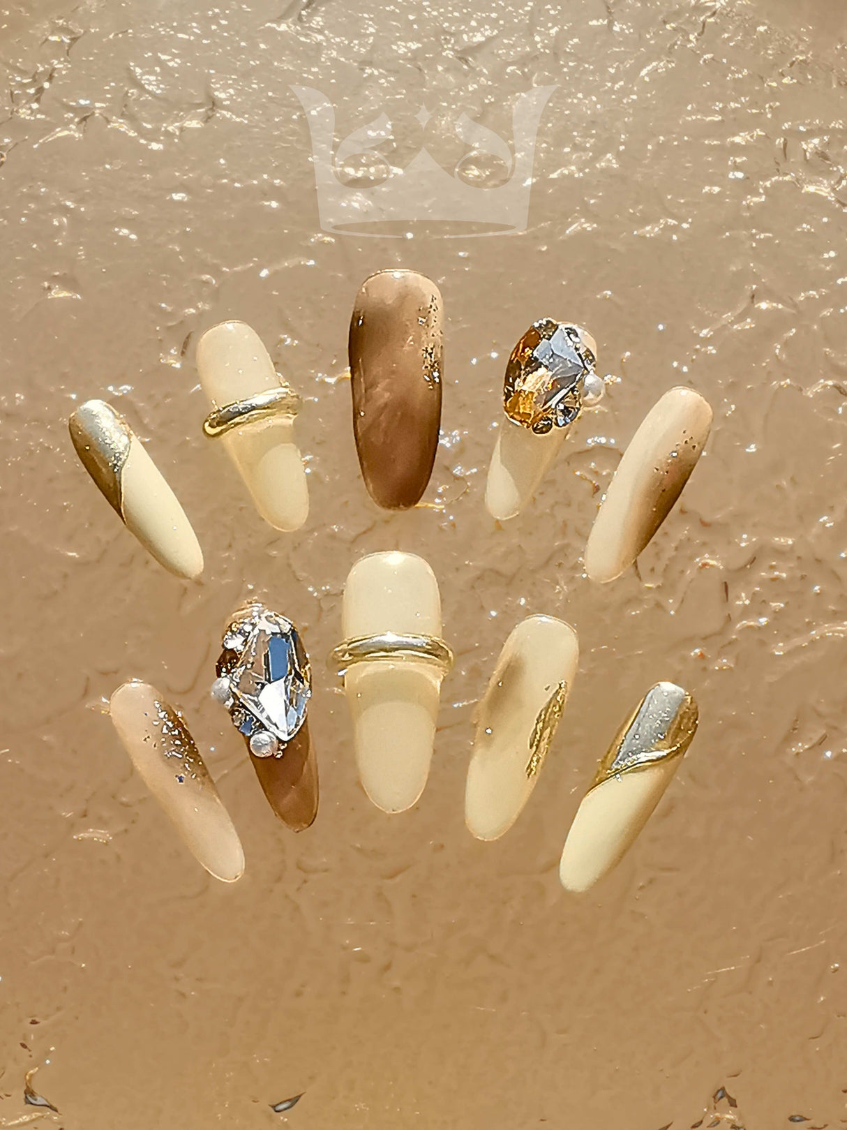 Sophisticated and elegant nails with metallic accents, rhinestones, glitter, and glossy finish. Suitable for special occasions or statement nail design.