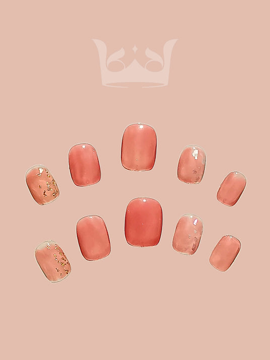 These press-on nails offer a touch of luxury and cute detail. They are minimalist yet chic design including a solid color base, soft pink color, gold embellishments, medium length, and squoval shape.