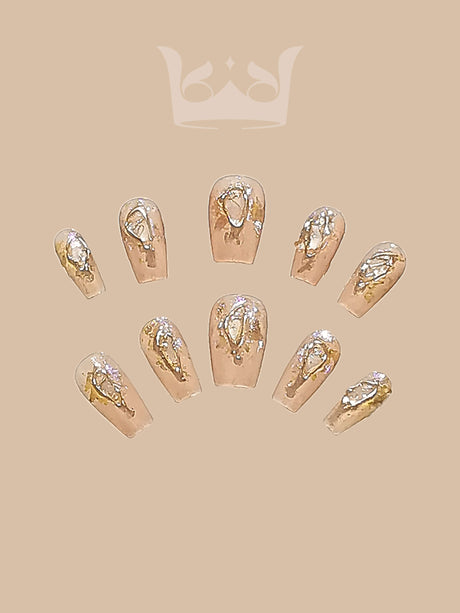Chic and versatile nails with nude base and gold foil accents towards tips, rounded/oval shape, suitable for everyday/formal occasions. Elegant and eye-catching.