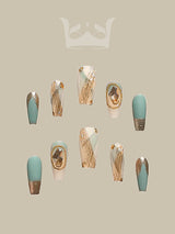 Trendy and stylish acrylic nails with gold foil/flake designs, geometric patterns, and central oval-shaped designs in a pastel teal color scheme. Ideal for special occasions or everyday wear.
