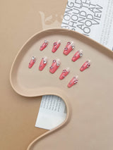 These press-on or nail extension nails feature a bold design with a bright pink base and a large rhinestone on each nail,  for fashion and personal style.