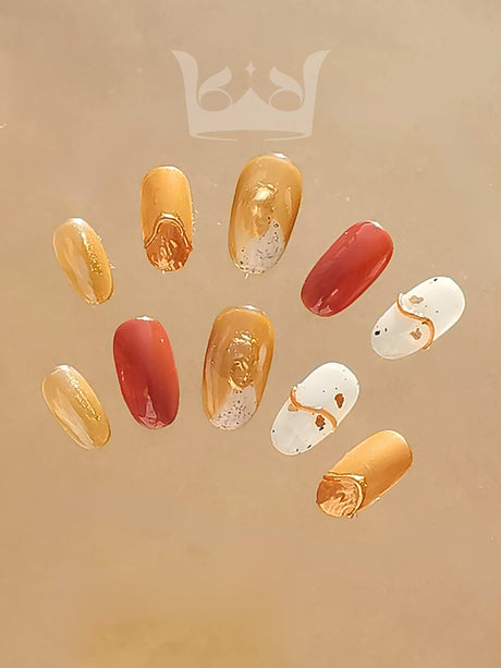 Fashionable and elegant acrylic nails with a mix of simplicity and ornate details. Color palette of gold, white, red, and brown with metallic sheen and speckled patterns.