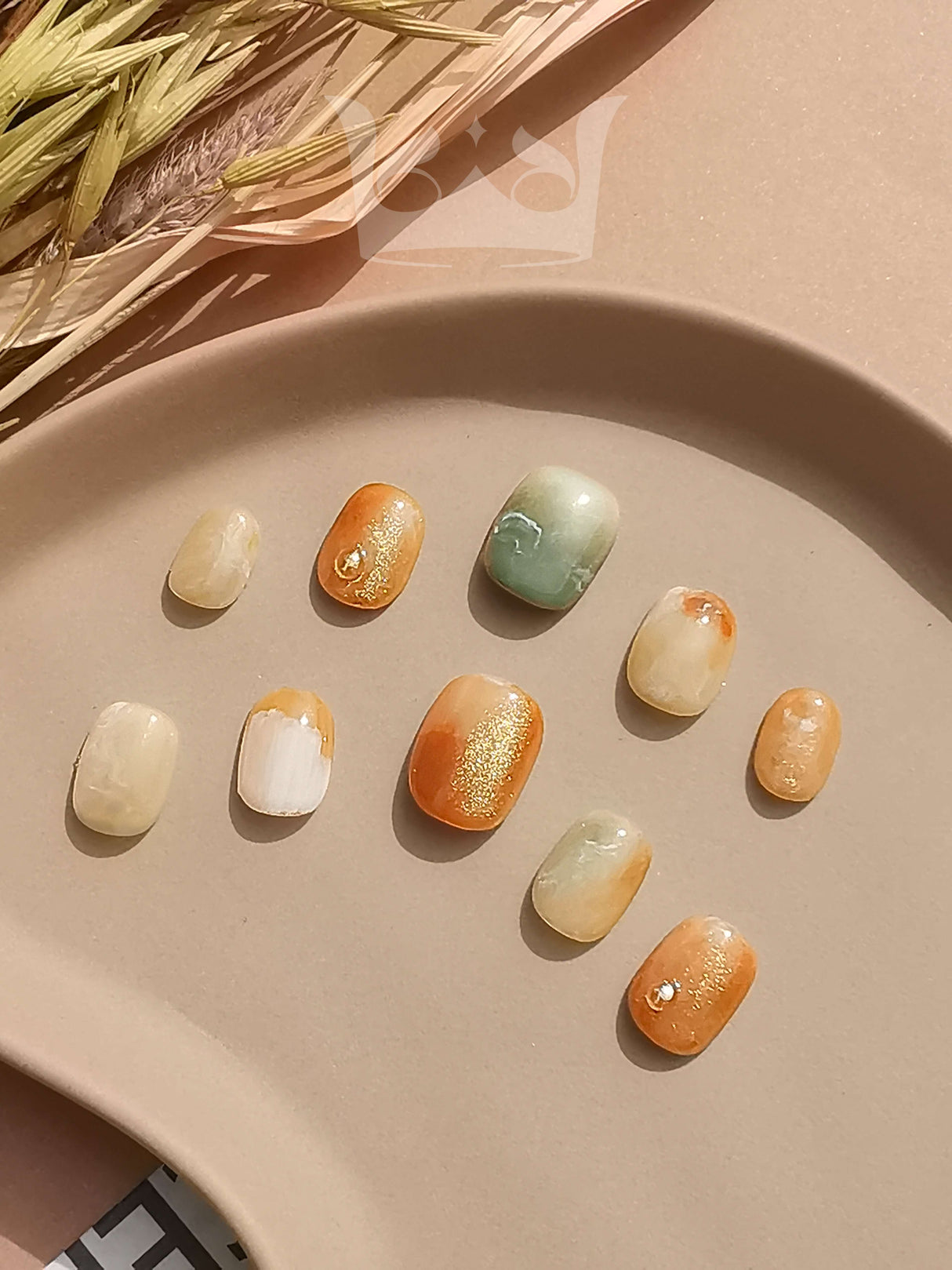 These oval-shaped acrylic nails with a natural stone effect and earthy tones are for a bohemian aesthetic. They have a shimmering finish for a touch of glamour.