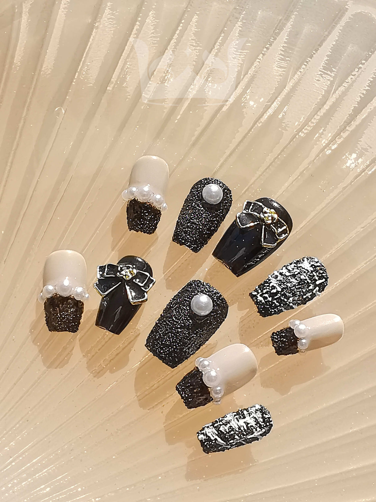 These press-on nails feature a fancy and glamorous design with a black and beige color scheme, 3D embellishments, and a marbled pattern.