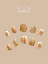 These press-on nails are perfect for a special occasion, with a luxurious and eclectic design featuring gold accents and a neutral base color.