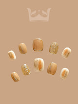 These press-on nails feature a minimalist design and gold accents. They feature varying lengths and a luxurious aesthetic with gold foil, glitter, and marble-like effects.