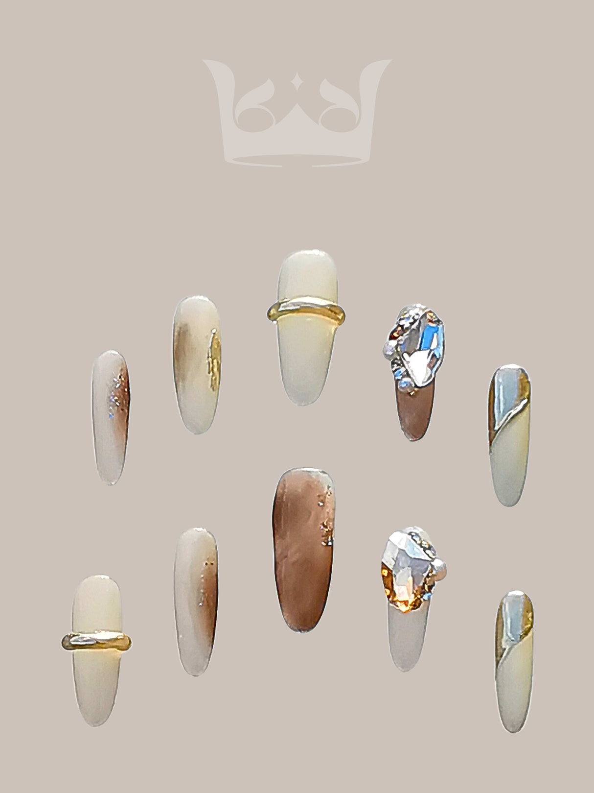 These press-on nails have a muted pastel color palette, gold bands, diamonds, and metallic accents, giving a fancy and understated style with a touch of luxury. 