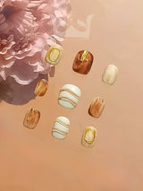 These stylish and modern acrylic nails are designed for nail art with metallic gold, white, gold stripes, glossy beige, and floral patterns.