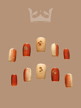 Stylish and cohesive nail art suitable for various occasions with warm, autumnal colors and cute accents. Varying in length with a uniform shape.