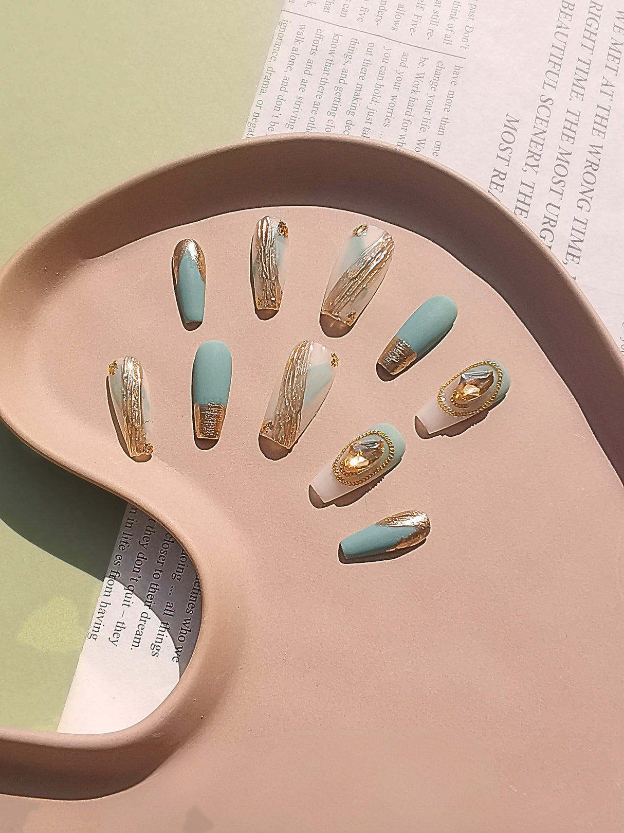 These press-on nails are  for cute purposes, with a dual-tone appearance, metallic gold accent, French tip effect, varying lengths, and oval tip shape. Displayed on a tray for aesthetic presentation.