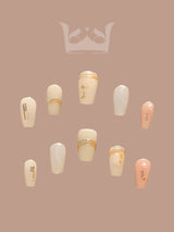 Sophisticated and elegant acrylic nails with neutral/pastel colors, gold accents, and metallic embellishments. Intended for fashion/cosmetic use. Regal design.